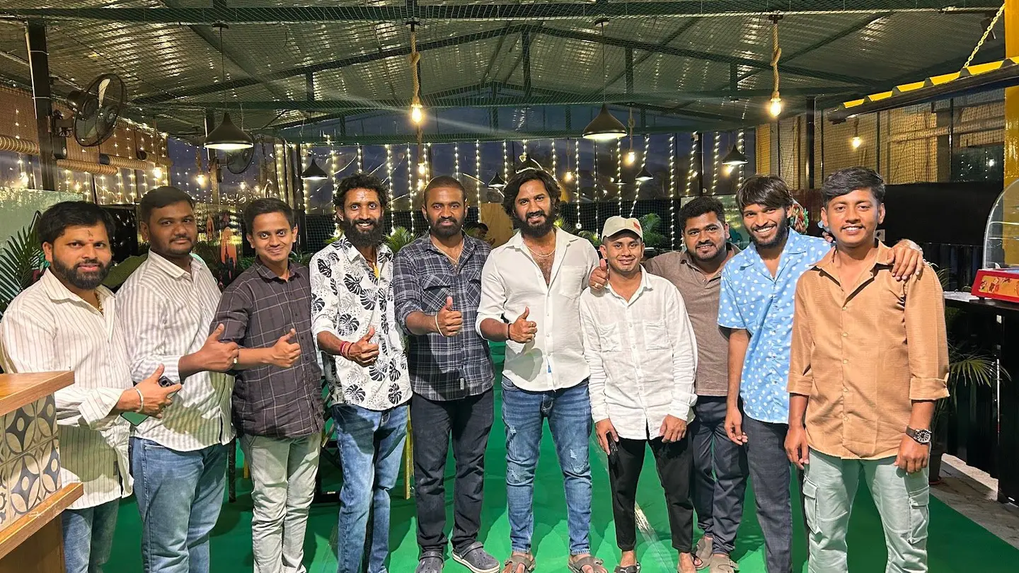 Seven of the team standing together under the fairy lights at night, giving a thumbs up.